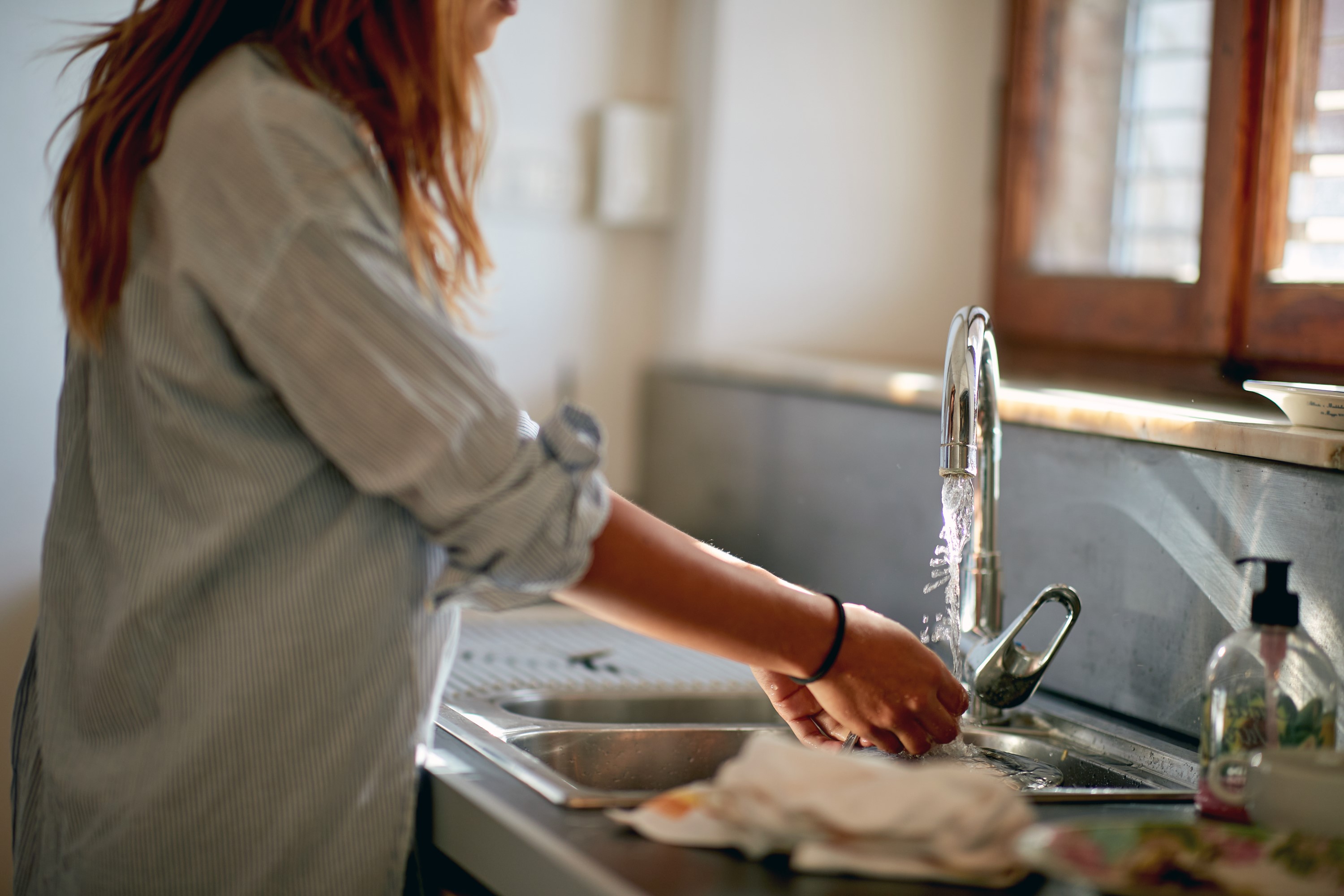woman washing hands in kitchen 